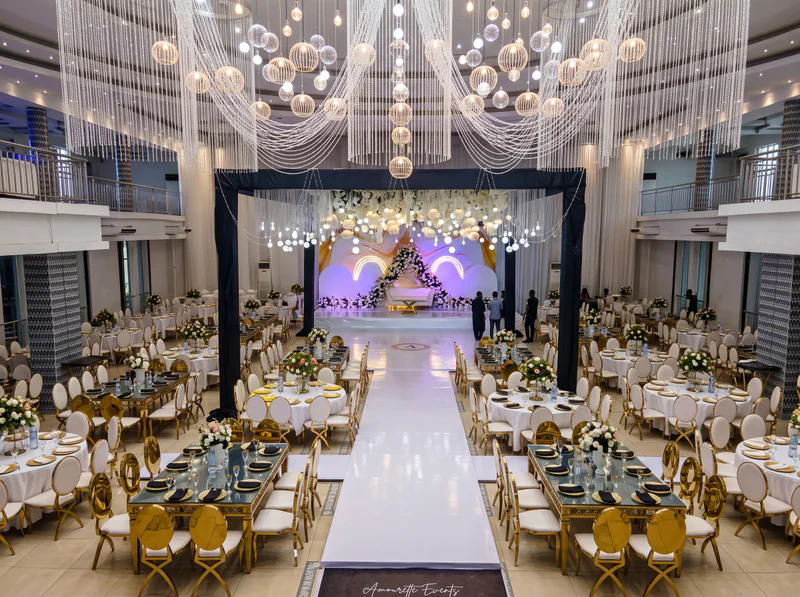 A decorated wedding hall with chandeliers and gold chairs